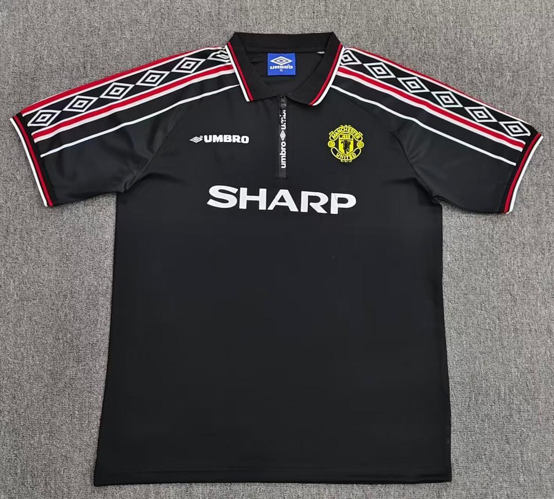 Black retro Manchester United Umbro jersey displayed on gray background.