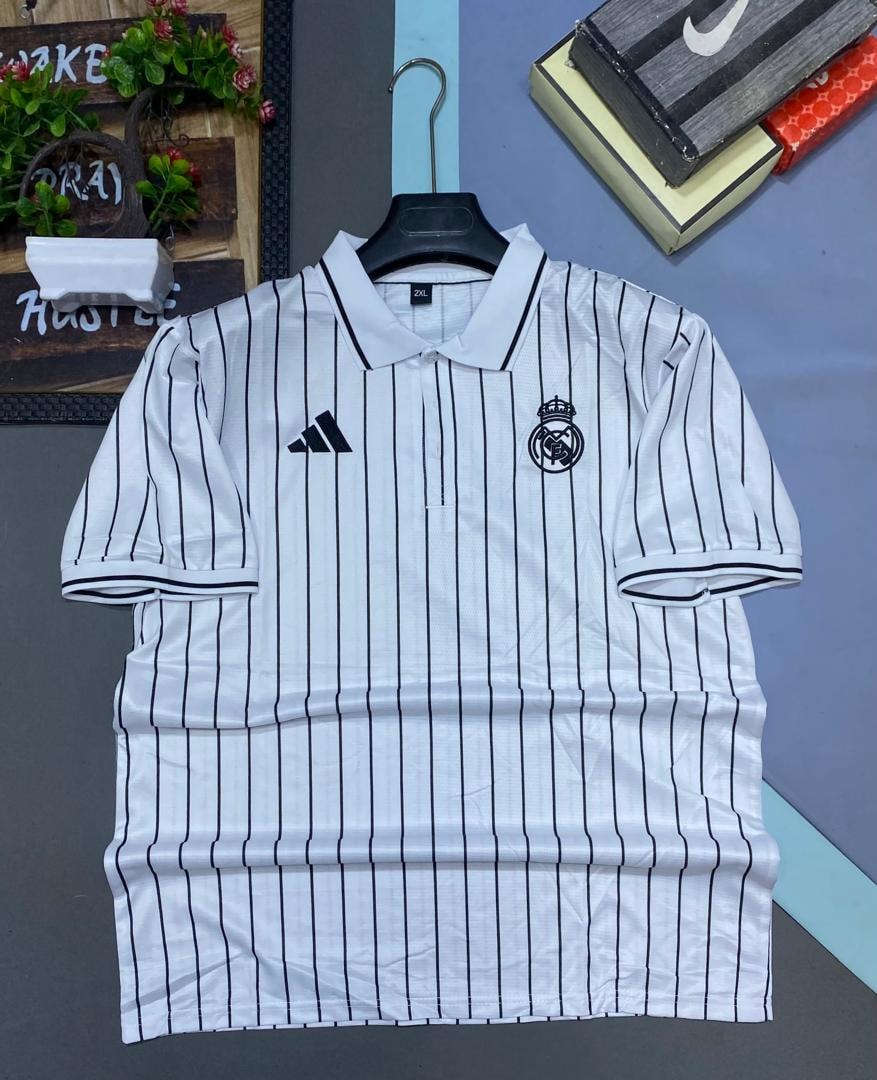 White and black striped Real Madrid polo jersey on hanger with decorations.