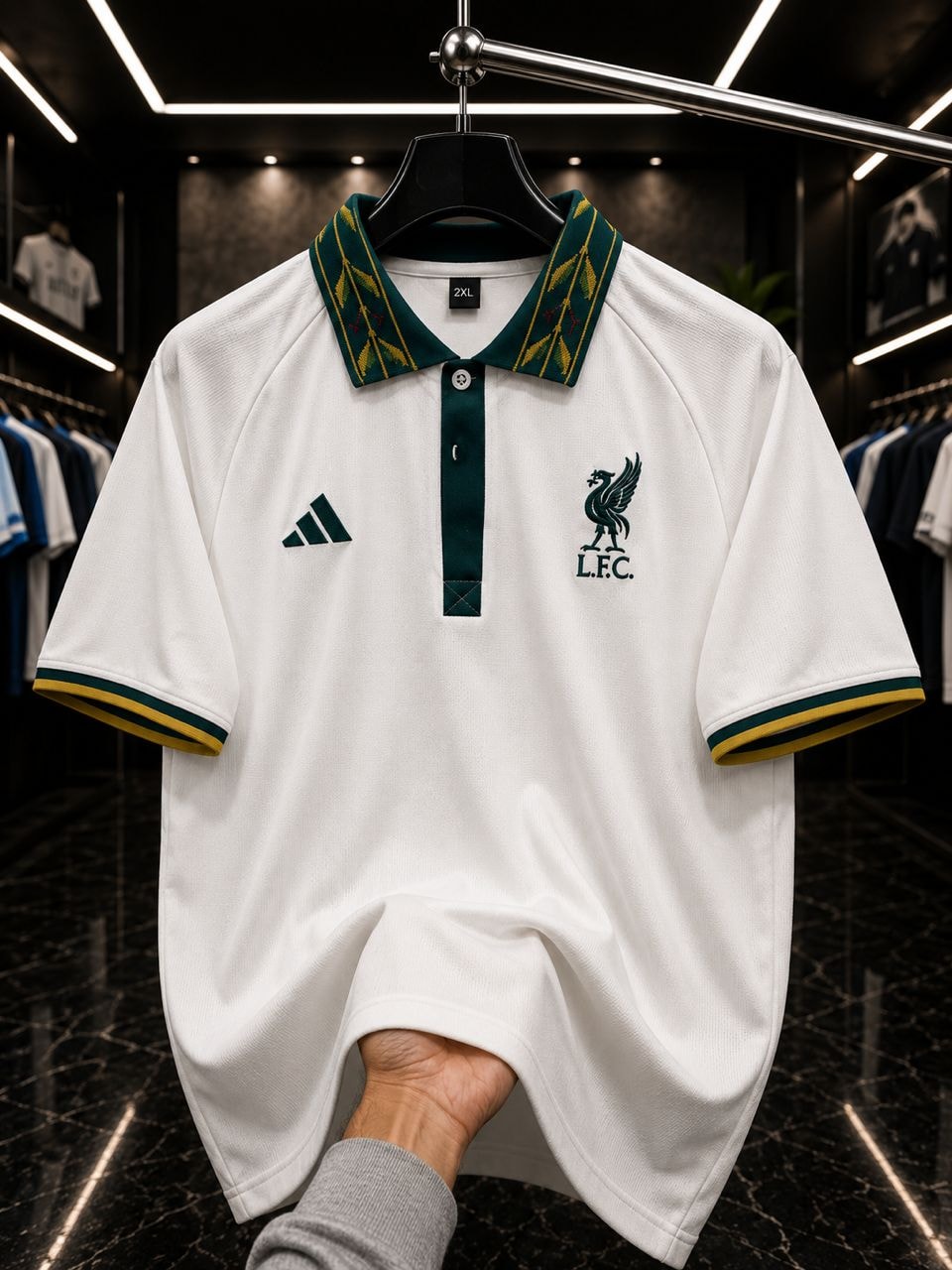 White Liverpool FC adidas polo with green collar on hanger in store.