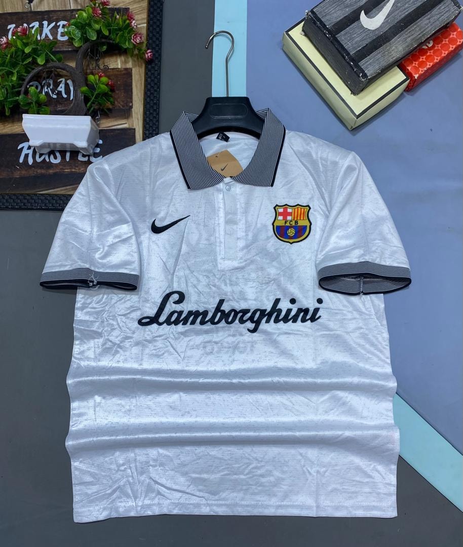 White retro Barcelona Nike polo jersey hanging against colorful background with decor.