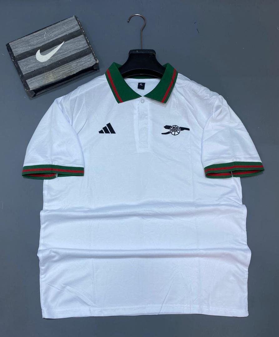 White Adidas Arsenal polo jersey with green red trim on hanger.