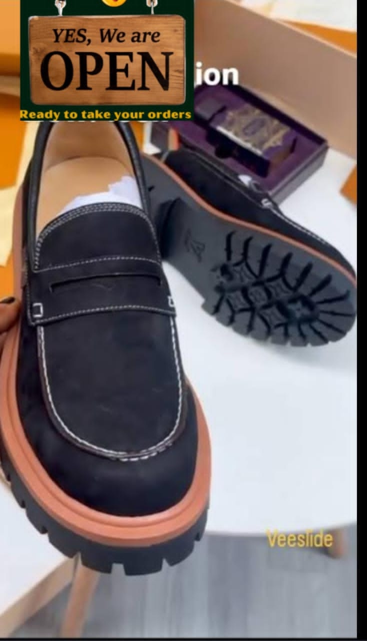 Black Louis Vuitton suede loafers with orange-brown chunky sole and luxury branding details.