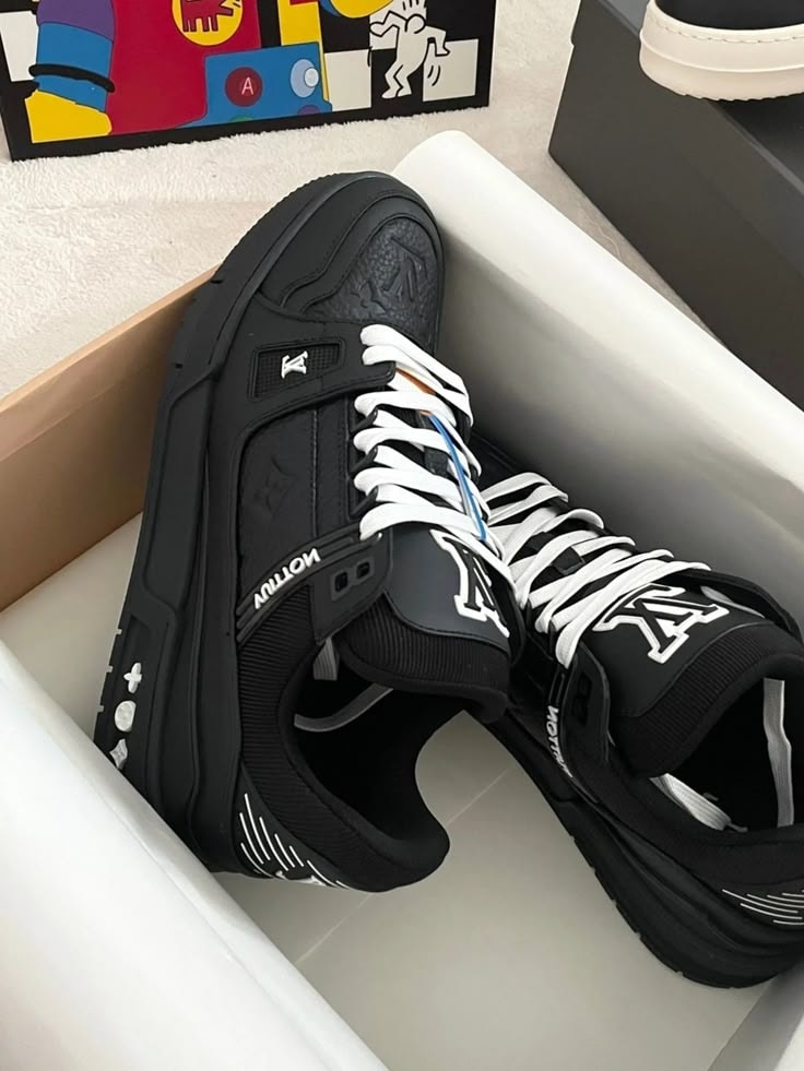 Black Louis Vuitton high-top sneakers with all-over LV logos in white box with art background.