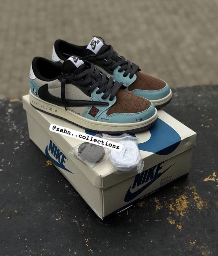 Travis Scott Nike Dunk Low in brown, black and blue resting on Nike shoebox with accessories.