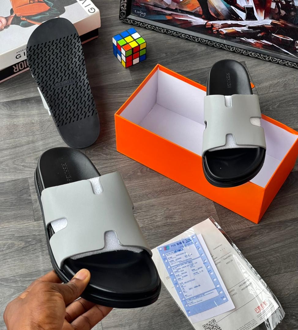 Grey slide sandal with H cutout design and black sole, displayed with box.