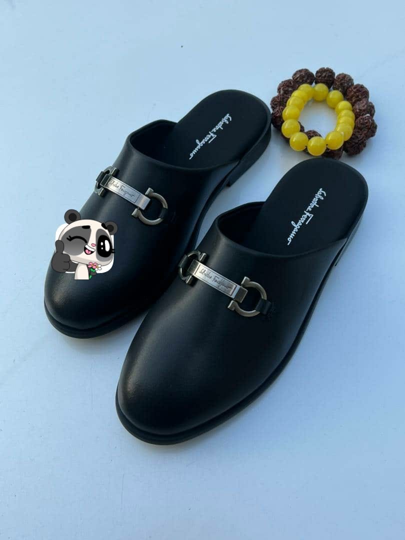 Pair of black Salvatore Ferragamo mules with buckles and branding, styled with beaded bracelet and panda emoji overlay.