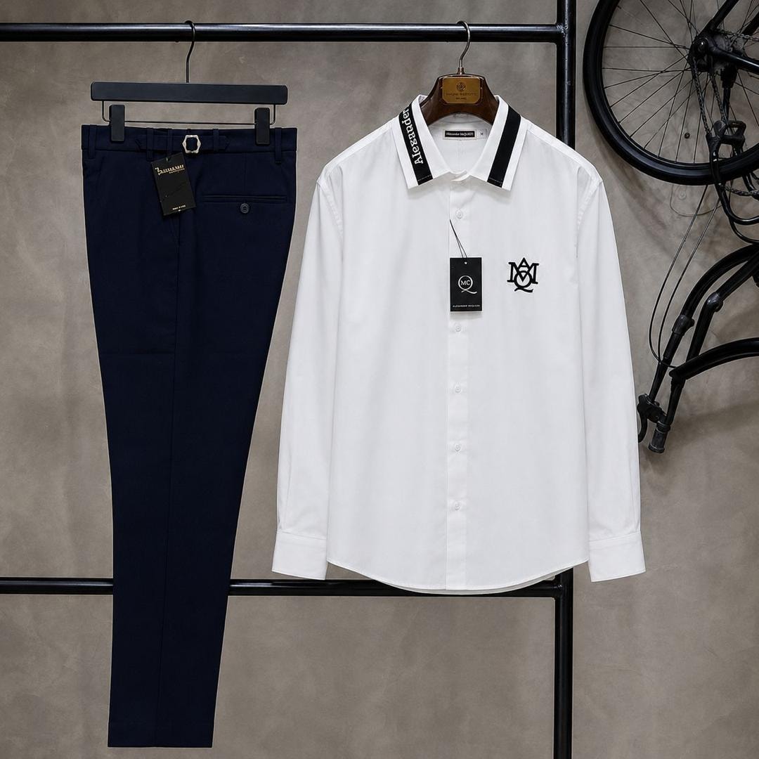 White long sleeve McQueen logo shirt paired with navy trousers on clothing rack.