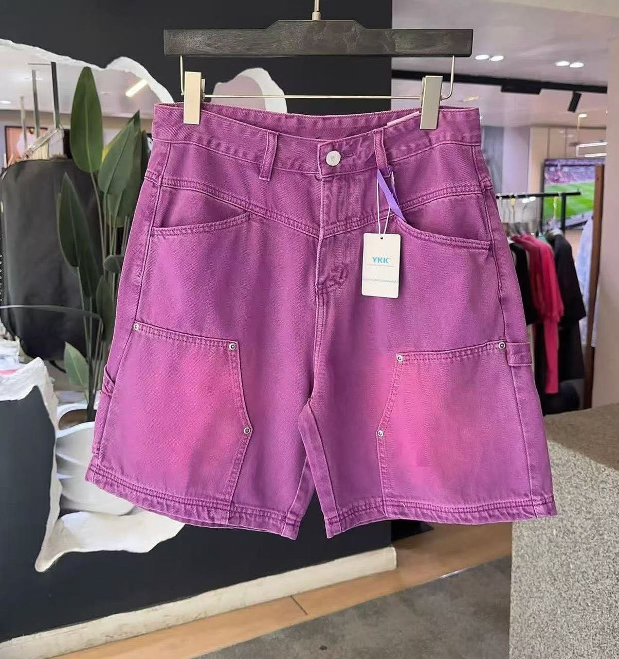 Purple faded cargo denim shorts on hanger in store.