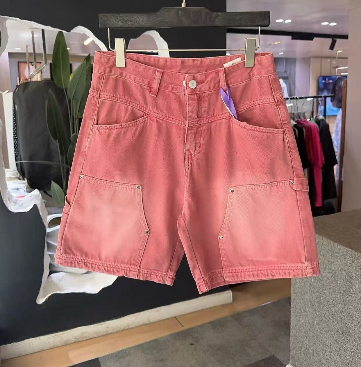 Pink faded cargo denim shorts on hanger in store.
