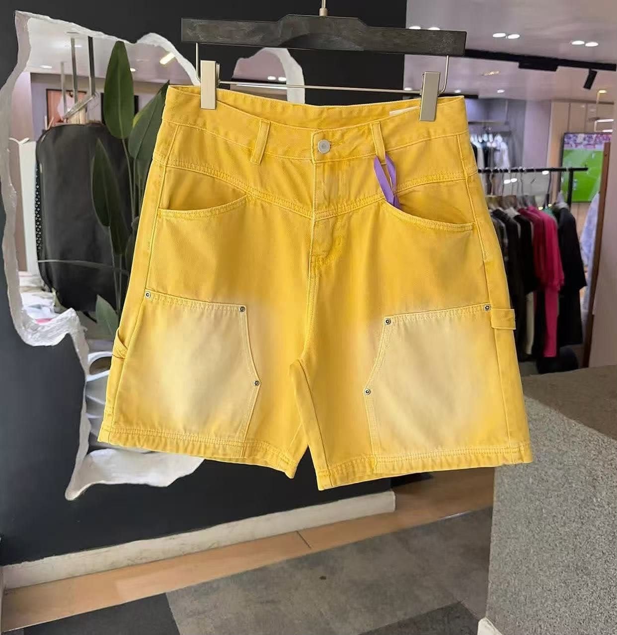 Yellow faded cargo denim shorts on hanger in store.