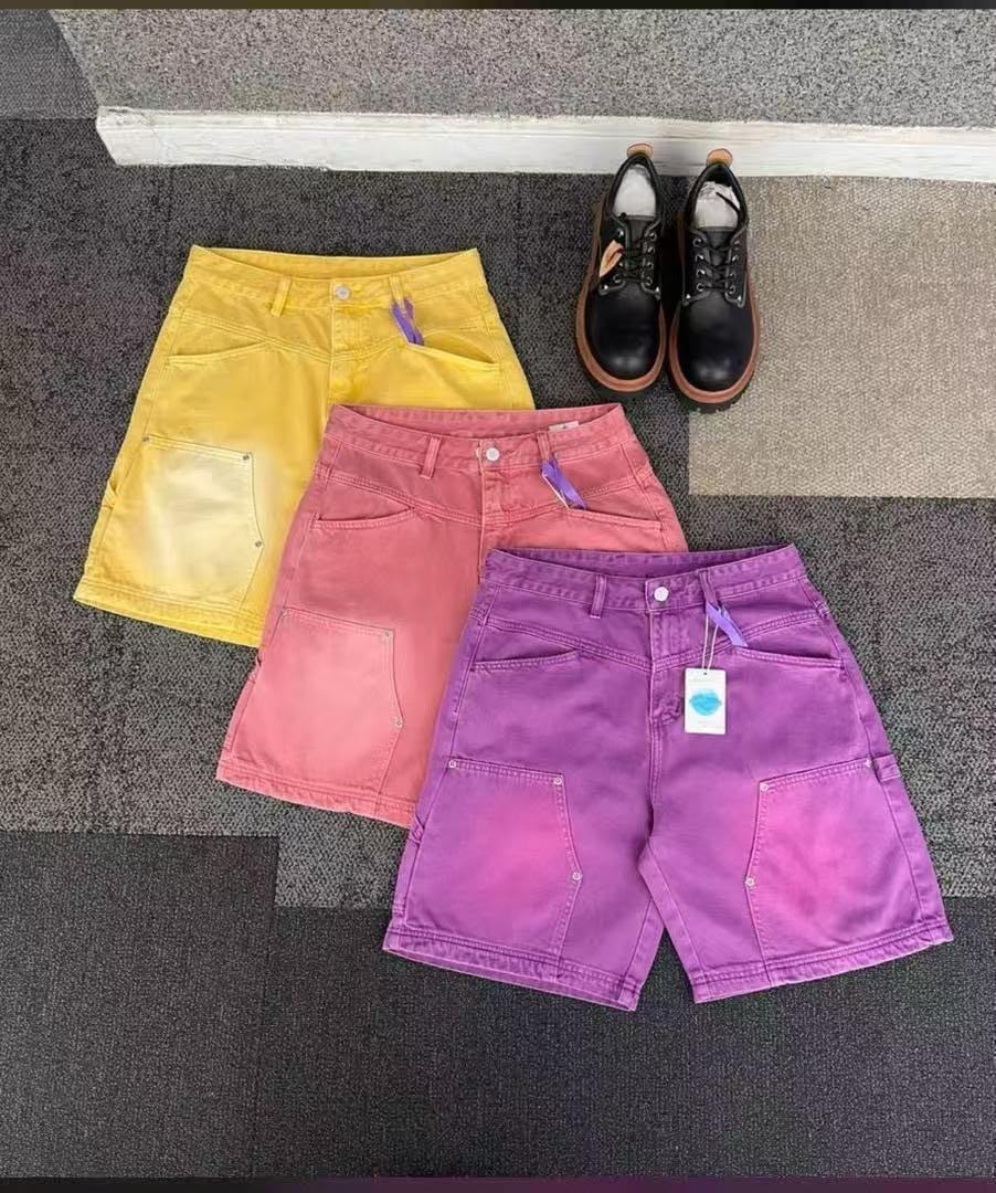 Faded cargo shorts in yellow, pink, and purple laid out with black boots.