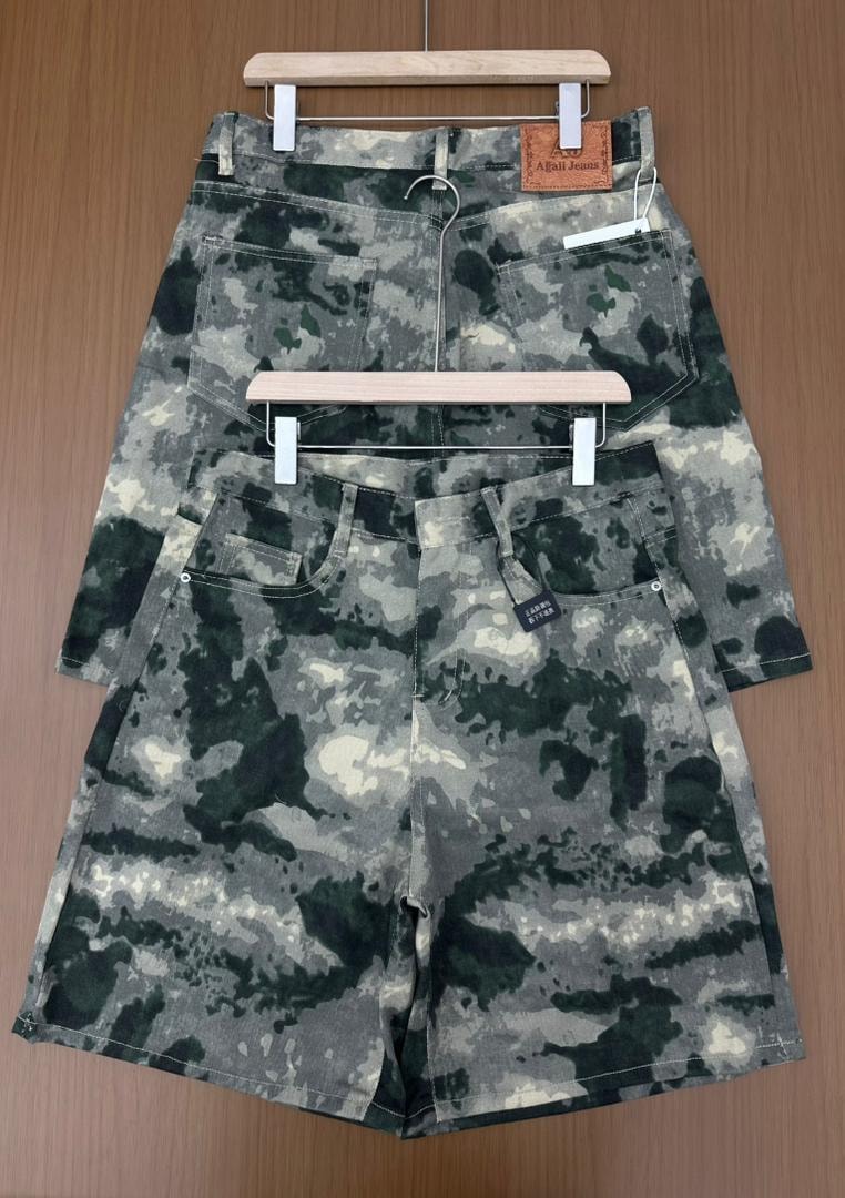 Front and back views of green camouflage denim jorts laid flat on wooden surface.
