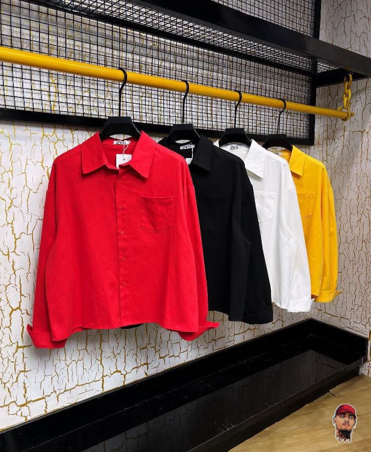 Four luxury update shirts in red, black, white and yellow hanging on a retail rack.