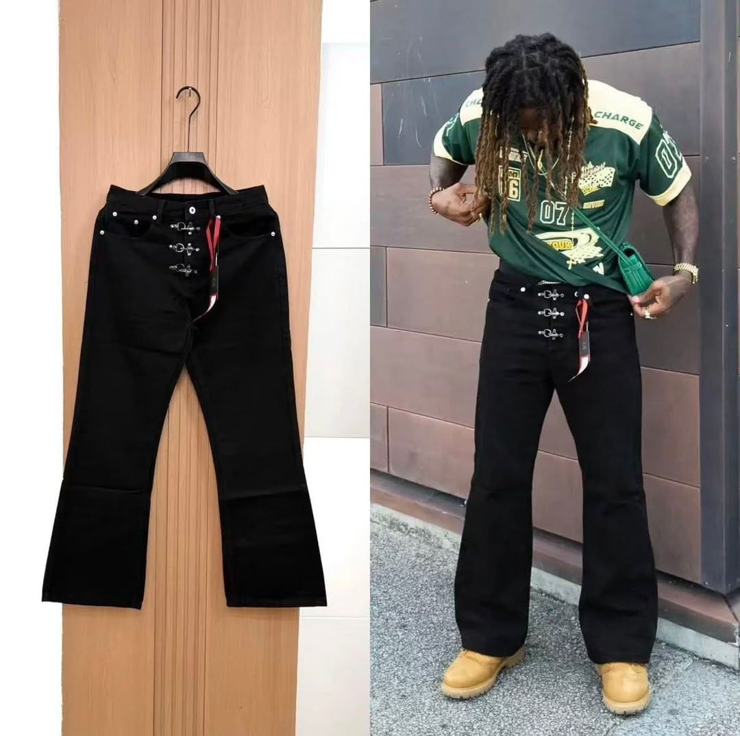 Black baggy jeans with silver eyelets shown flat on hanger and worn by model outdoors.