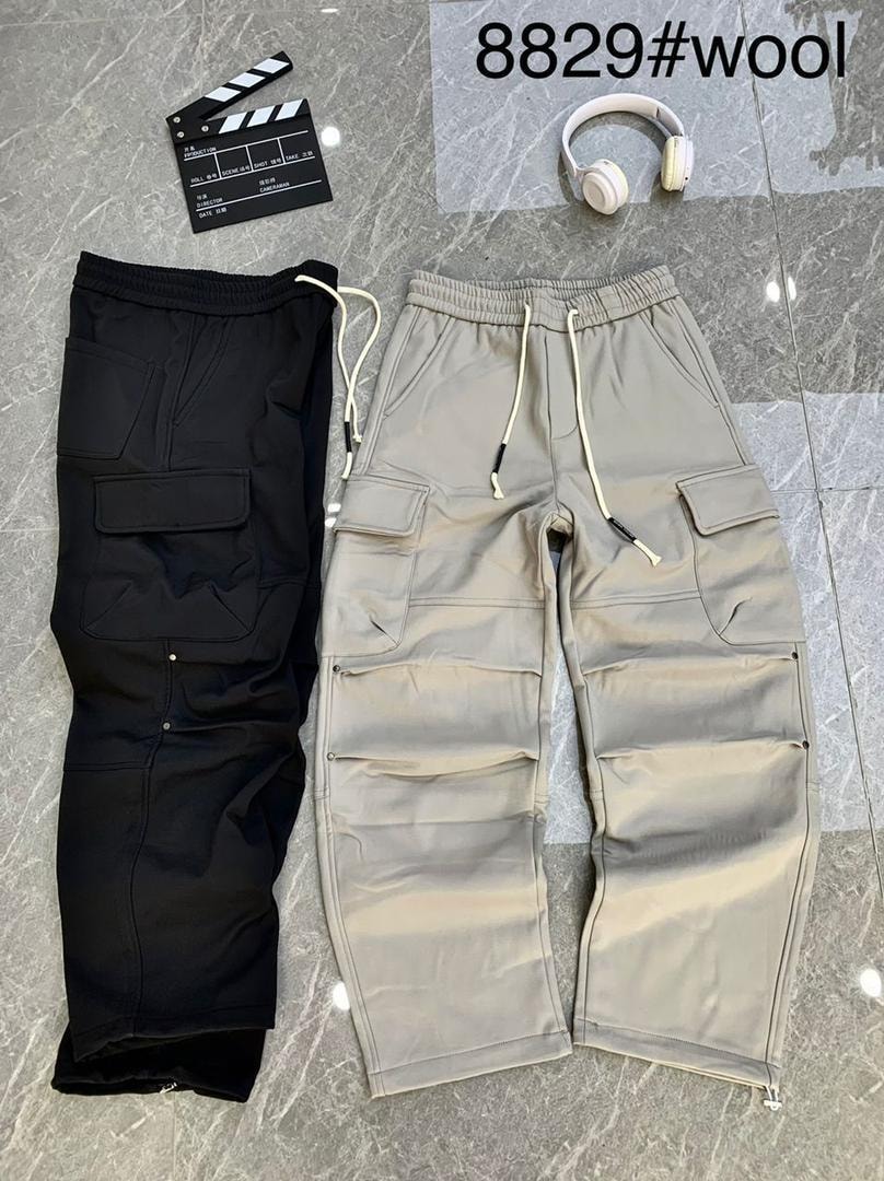 Black and beige cargo jogger pants laid flat on marble with clapperboard and headphones.