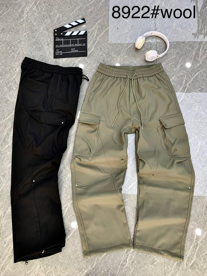 Black and olive green cargo jogger pants laid flat on marble with clapperboard and headphones.
