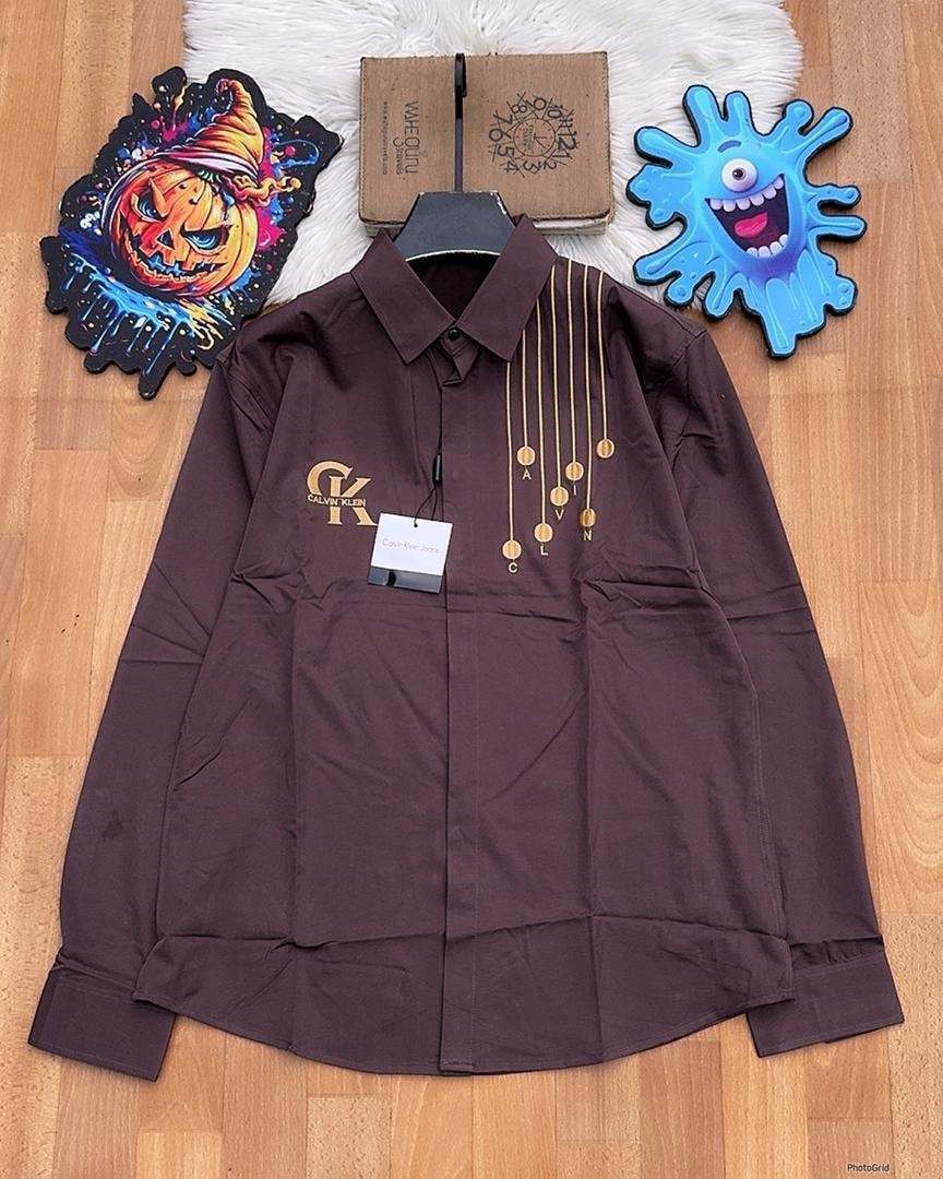 Brown Calvin Klein embroidered long sleeve button-down shirt laid flat on wooden floor.