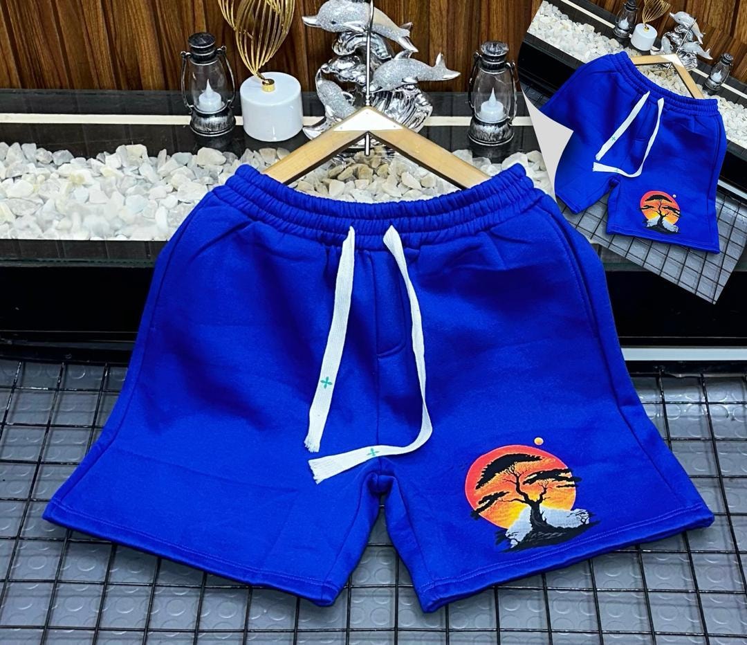 Blue fleece shorts with embroidered sunset tree design on the leg.