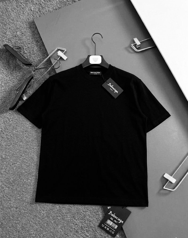 Black plain polo shirt laid flat showing short sleeves, crew neck and Balenciaga tags.