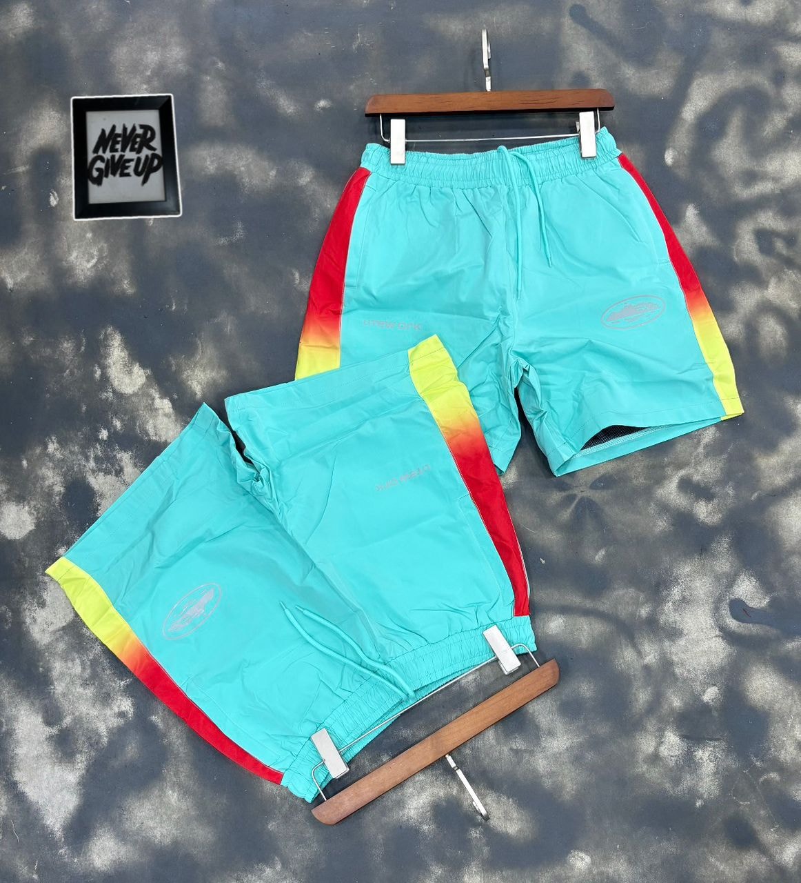 Teal Litework gradient track shorts on hanger and flat lay.