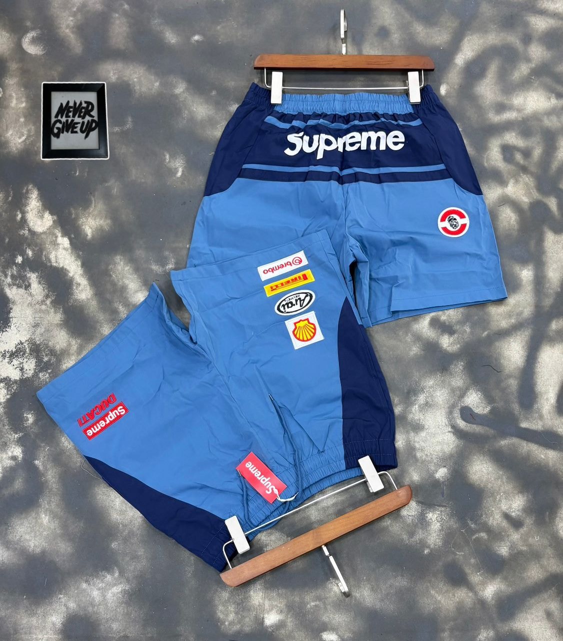 Supreme patch shorts in blue on hanger and flat lay with visible logos.