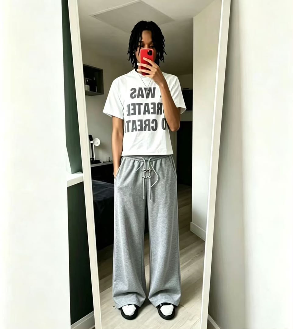 Model wearing gray wide-leg jogger trousers with drawstring detail in mirror selfie.