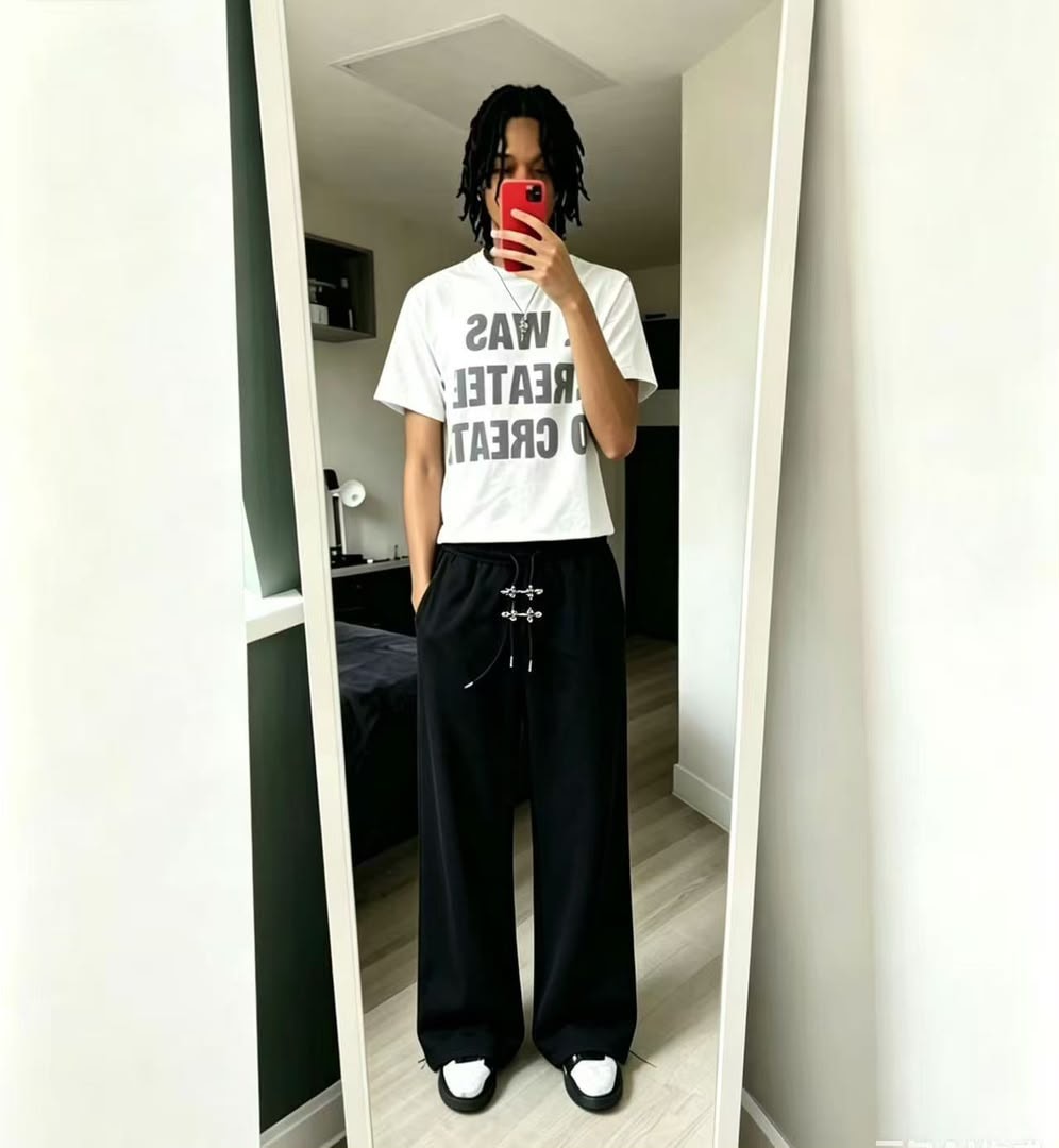 Model wearing black wide-leg jogger trousers with drawstring detail in mirror selfie.