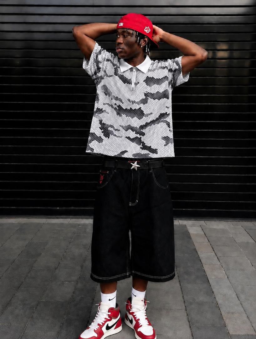Model wearing gray camouflage Majestic zip polo shirt with red cap and black shorts.