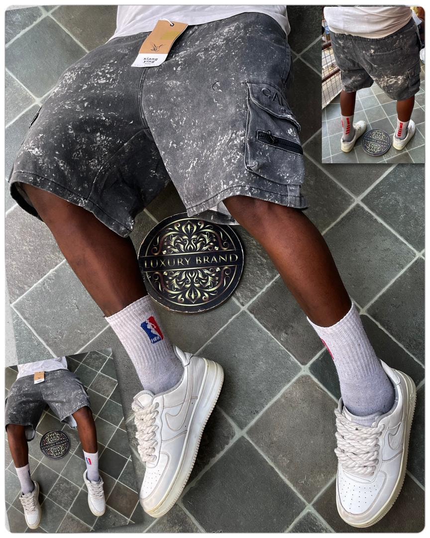 Rear view of model in gray splatter camo cargo shorts with white sneakers.