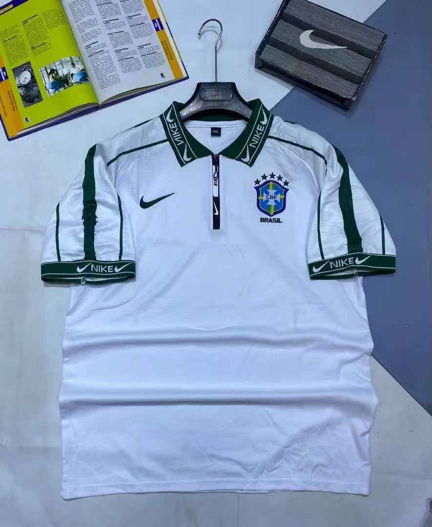 White and green Nike Brazil football jersey on hanger with background items.
