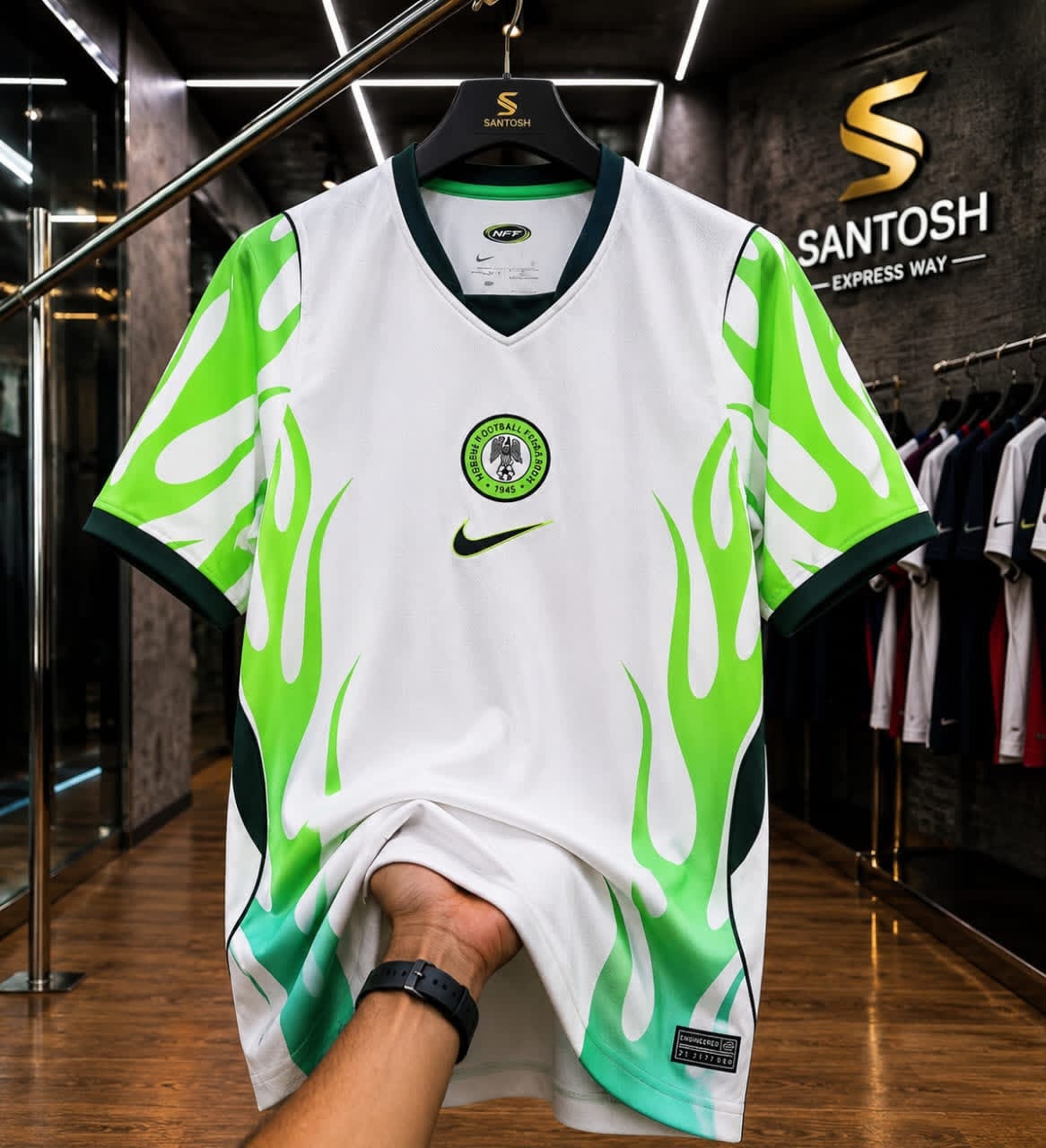 White and green flame Nike Nigeria football jersey held up in store.