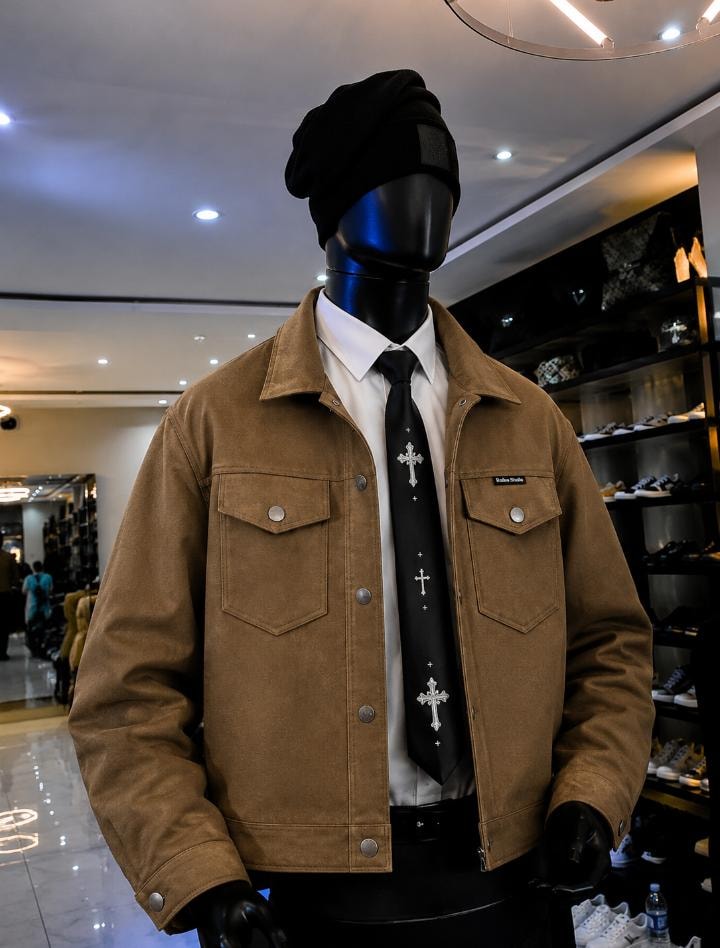 Mannequin in brown suede trucker jacket styled with white shirt and black cross tie.