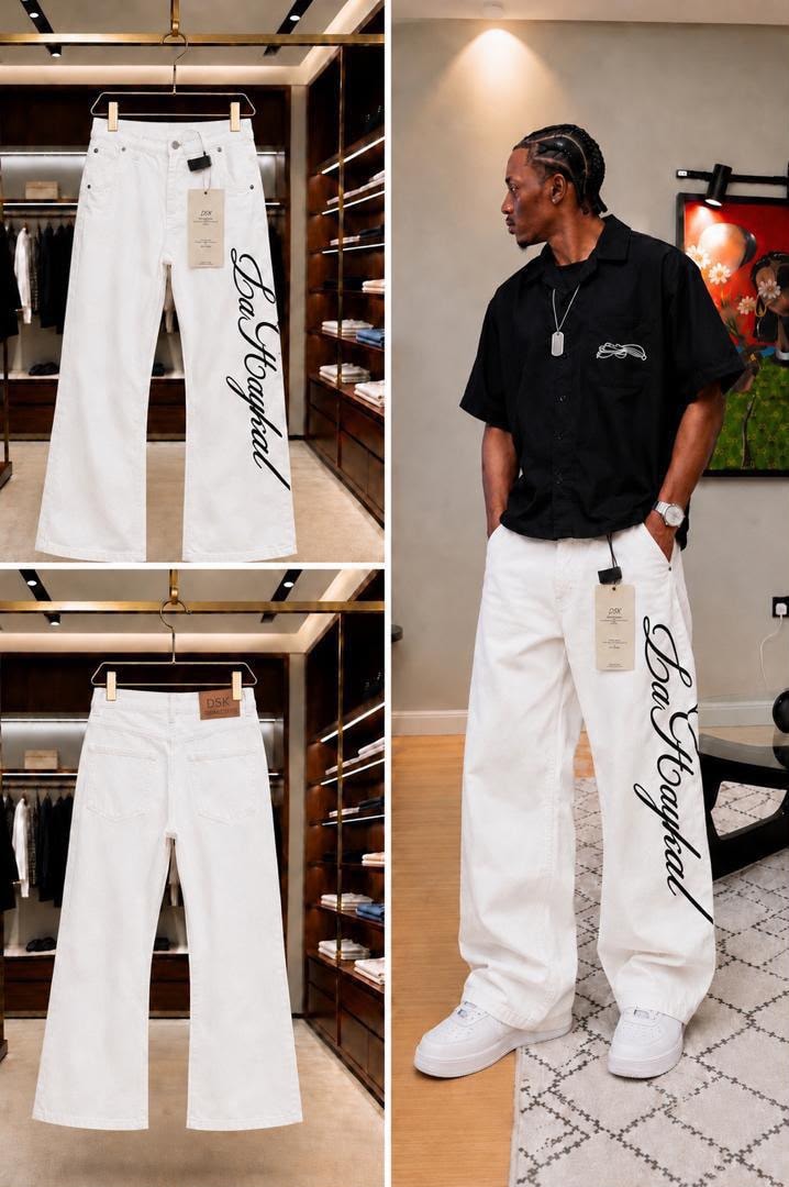 White baggy jeans with black cursive print, shown hanging and on model with black shirt.