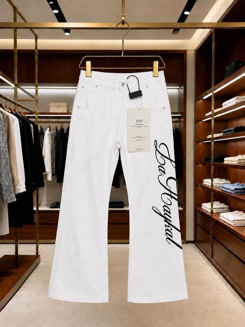 White baggy jeans with black cursive side print hanging in a retail store.