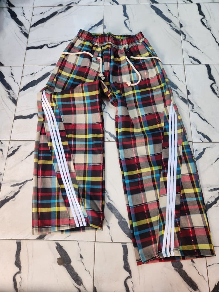 Red multicolored plaid joggers with white side stripes laid flat.