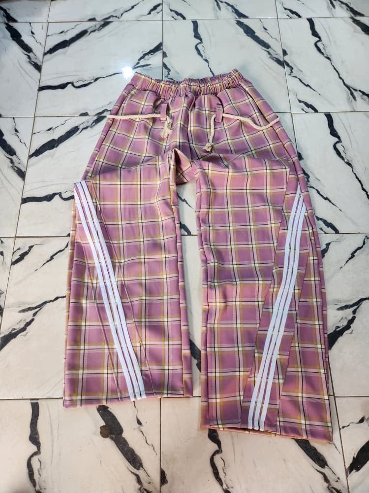 Pink plaid joggers with white side stripes laid flat.