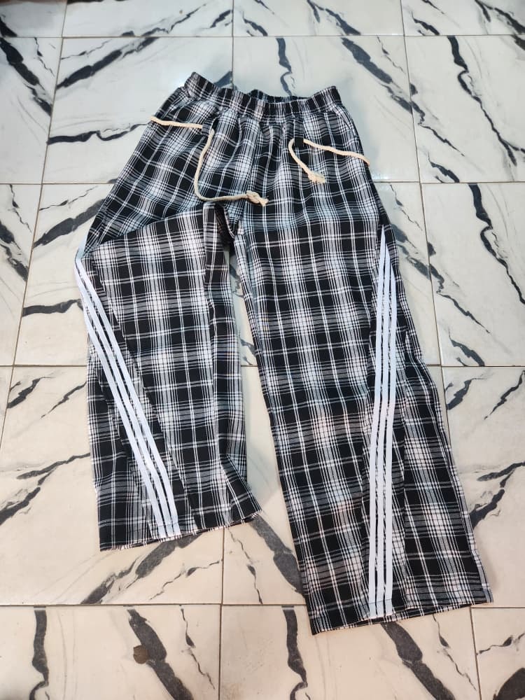 Black plaid joggers with white side stripes laid flat.