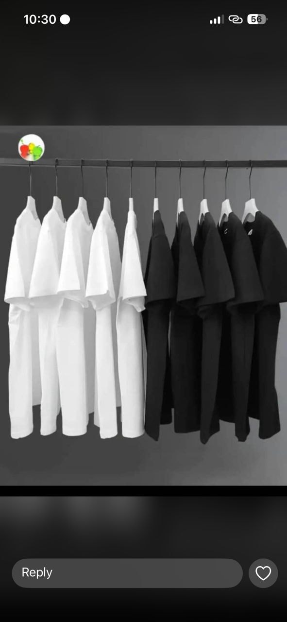 Multiple white and black oversized t-shirts displayed on a clothing rack.