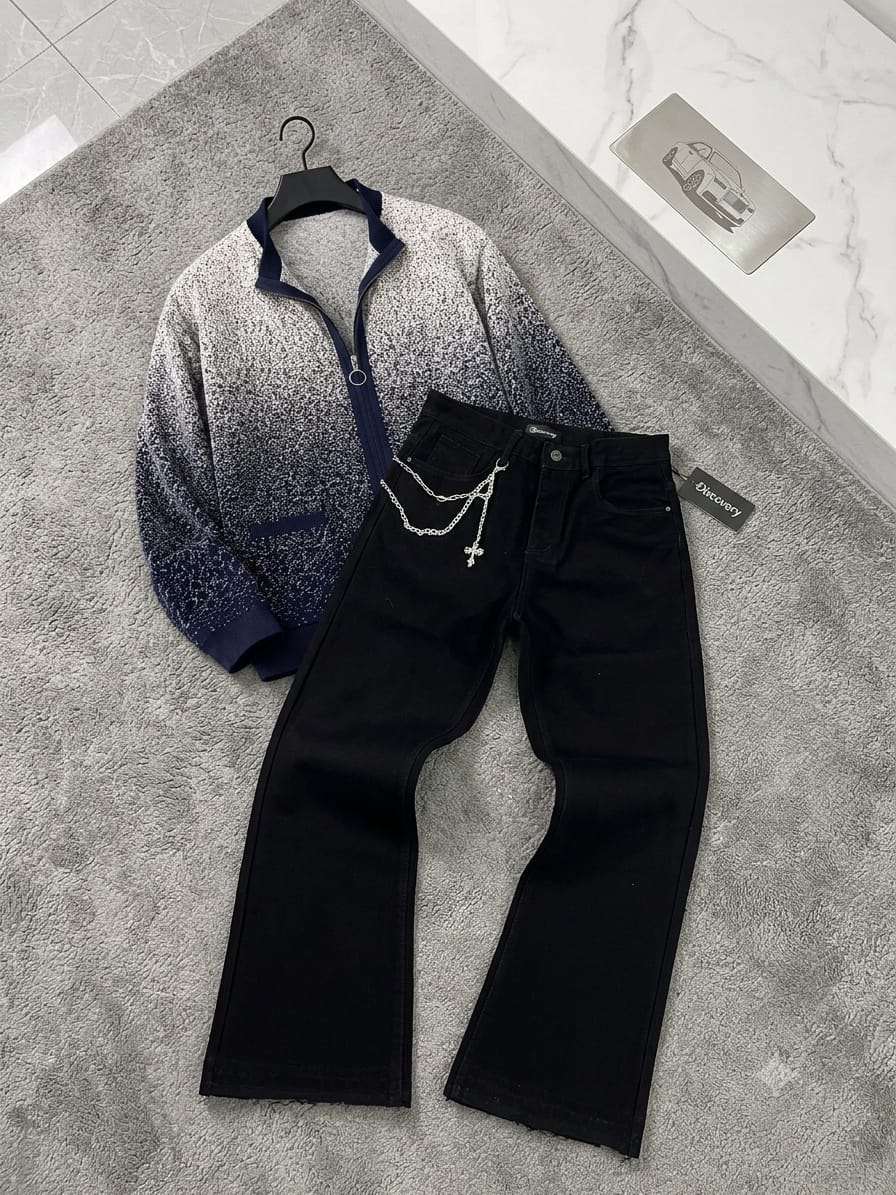 Speckled blue-white zip-up sweater and black jeans with cross chain on gray rug.