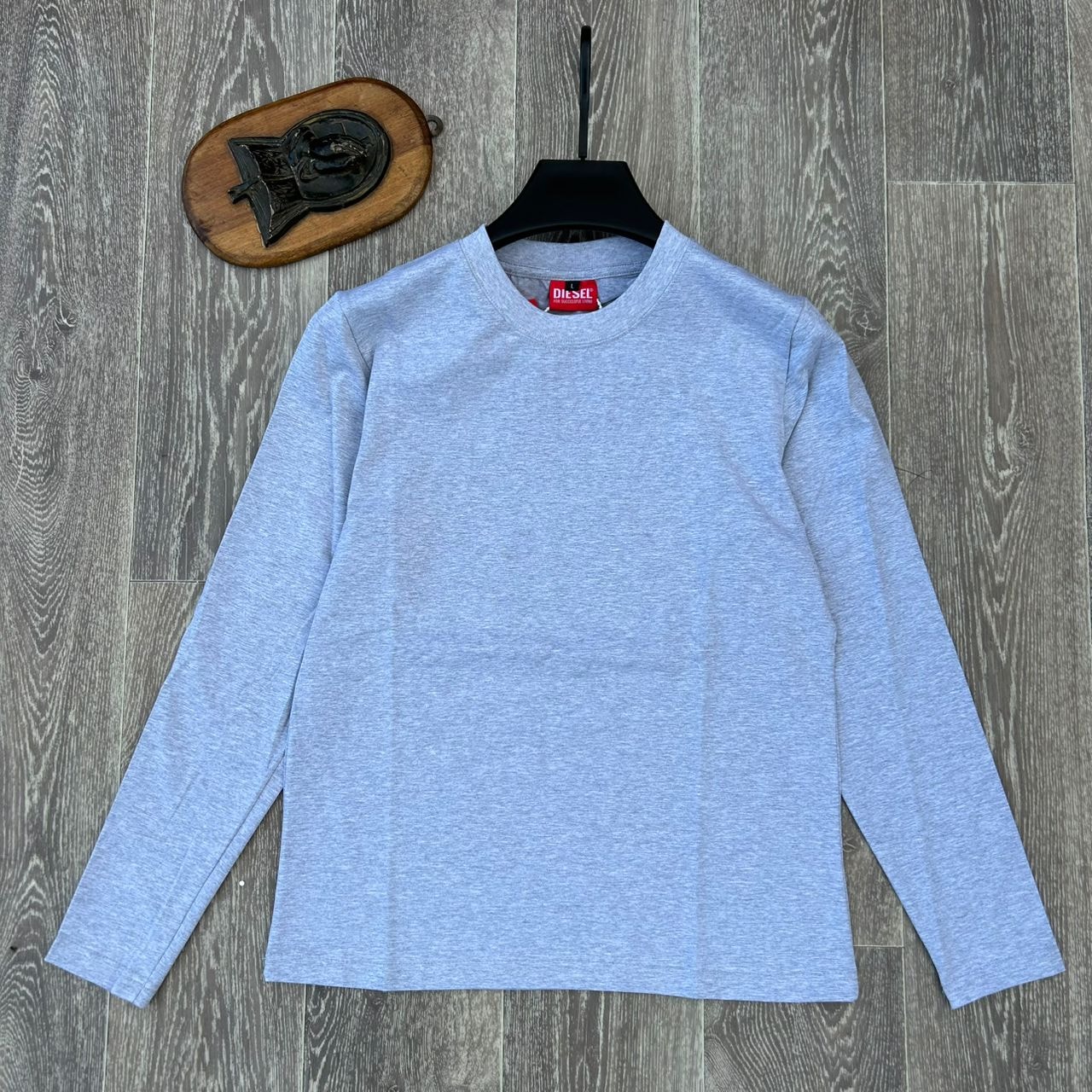 Gray plain body hug long sleeve top on hanger against wooden background.