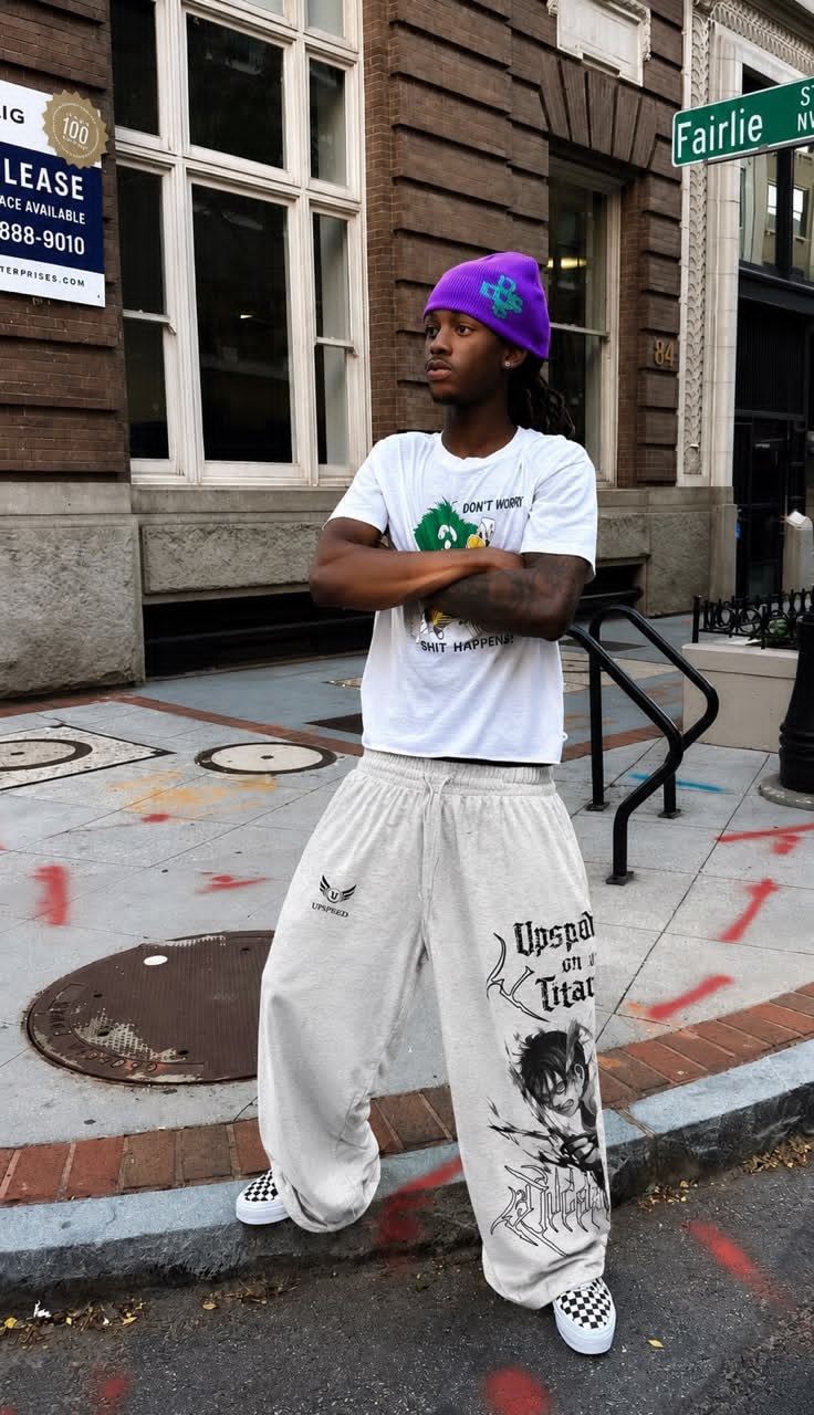 Man wearing light grey Upspeed graphic joggers with anime print and text on the leg, styled with white t-shirt and purple beanie.