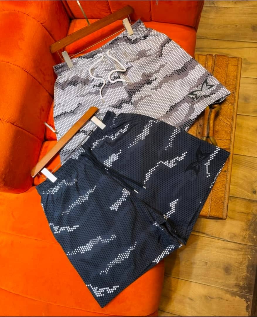 Gray and navy NIKA perforated pattern shorts displayed side by side.