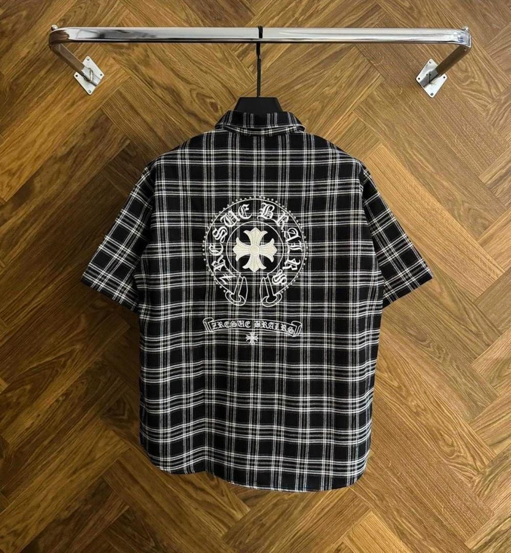 Back view of black plaid shirt with prominent white circular print and cross.
