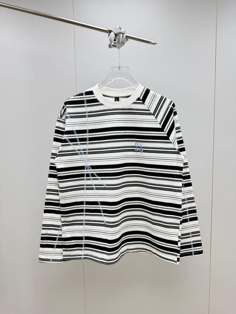 Black and white striped long sleeve top hanging on display.