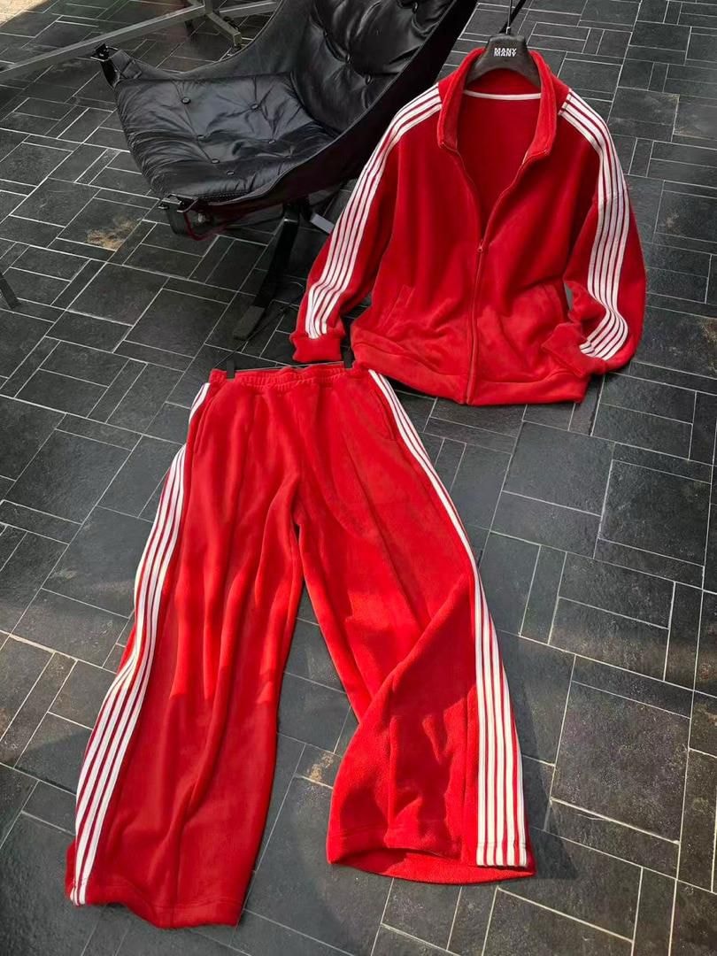 Red velour tracksuit set with jacket and pants on tiled floor.