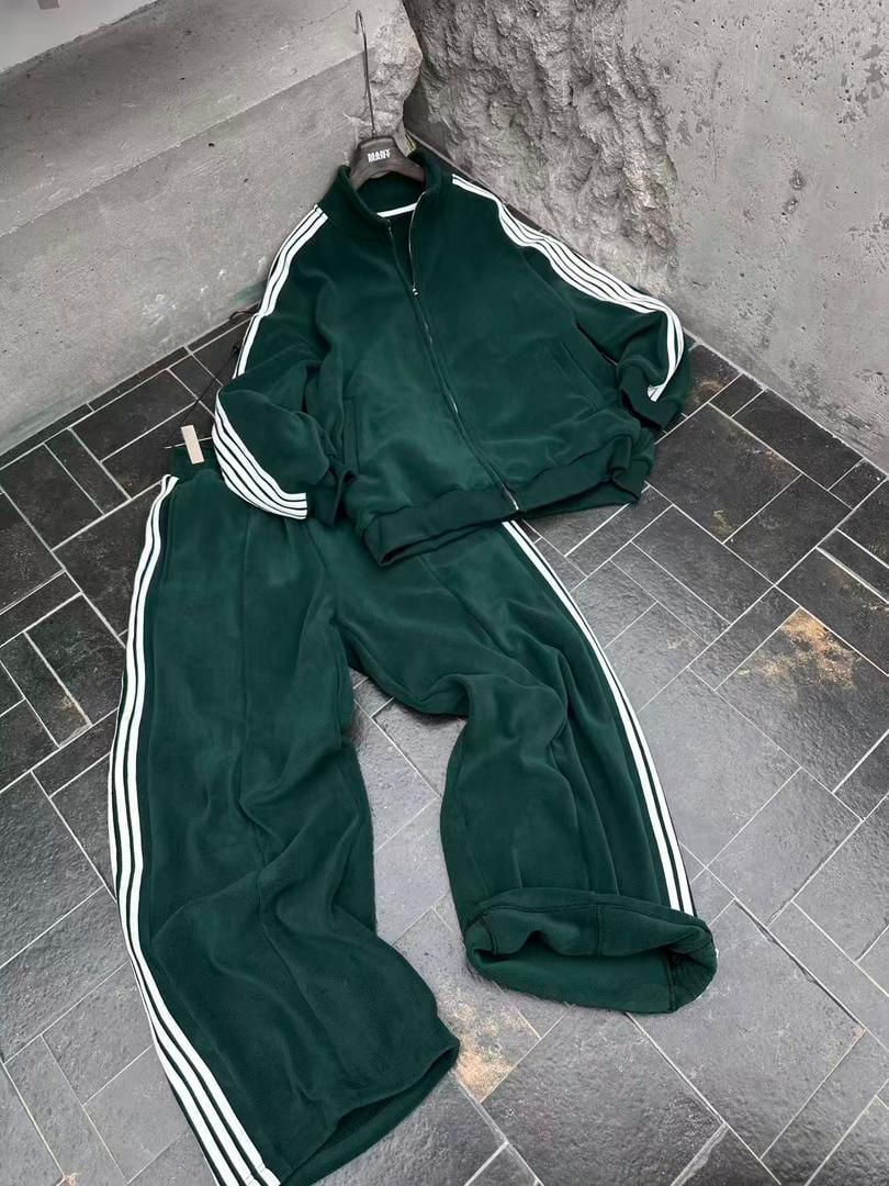 Flat lay of green velour tracksuit set on tiled floor.