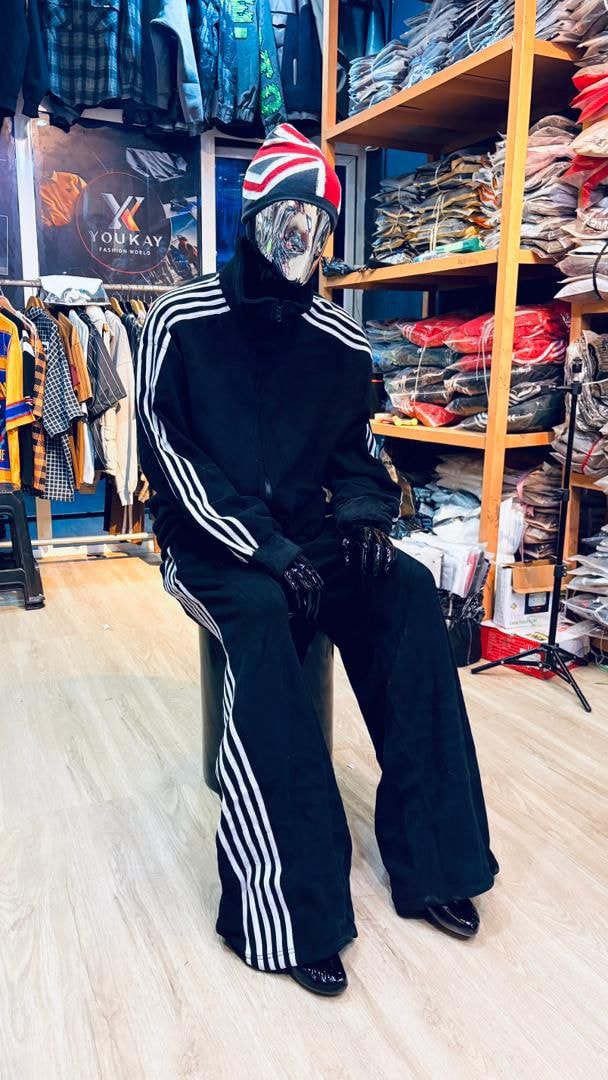 Mannequin in black velour zip-up tracksuit with white stripes and flared pants.