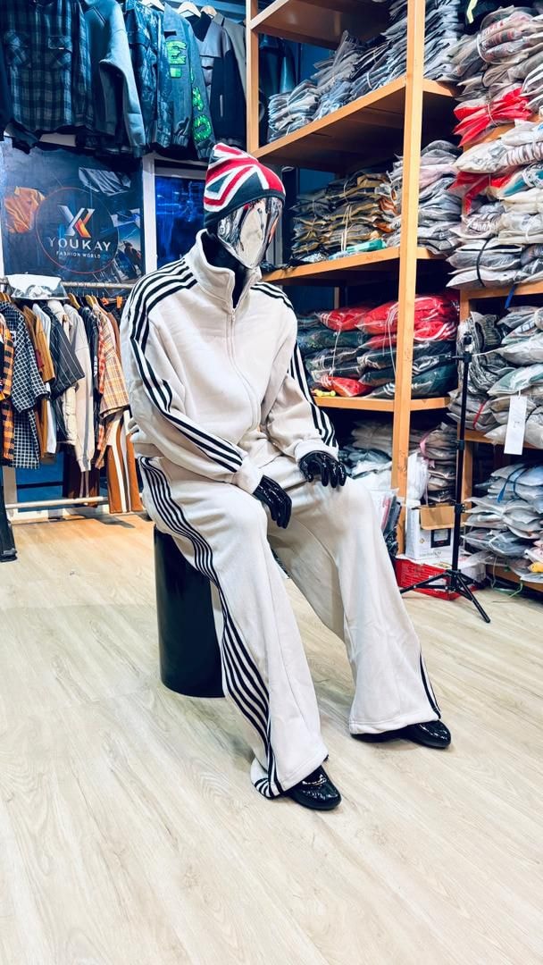 Mannequin in cream velour zip-up tracksuit with black stripes and flared pants.