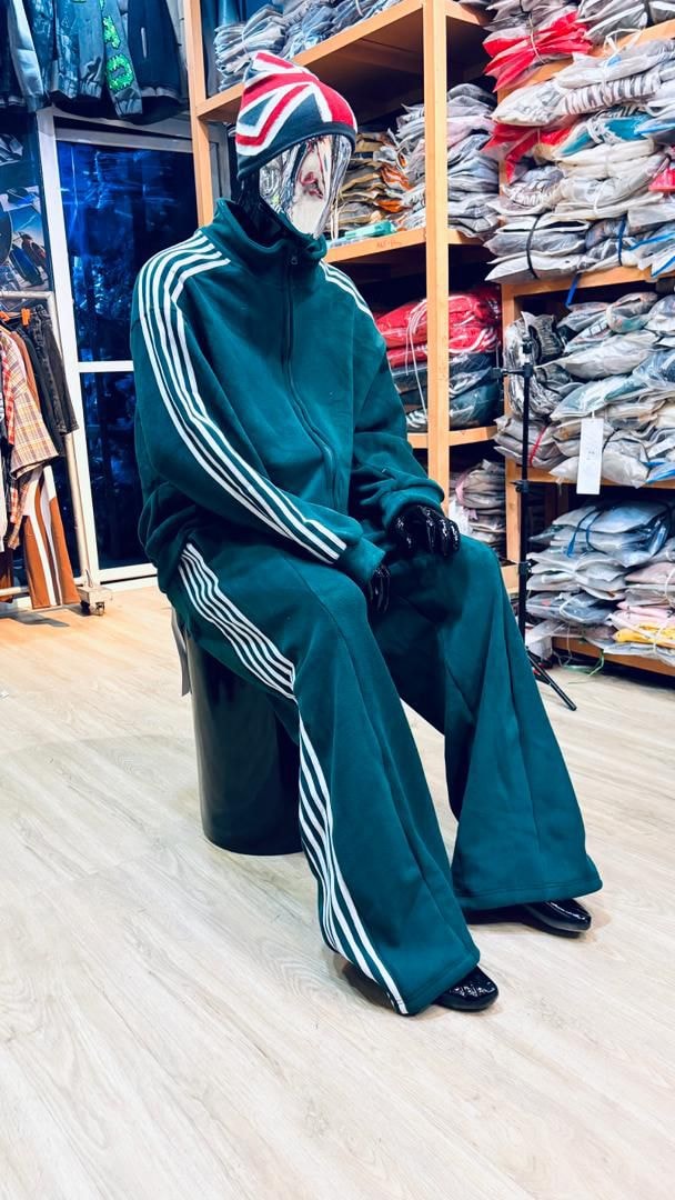 Mannequin in green velour zip-up tracksuit with white stripes and flared pants.