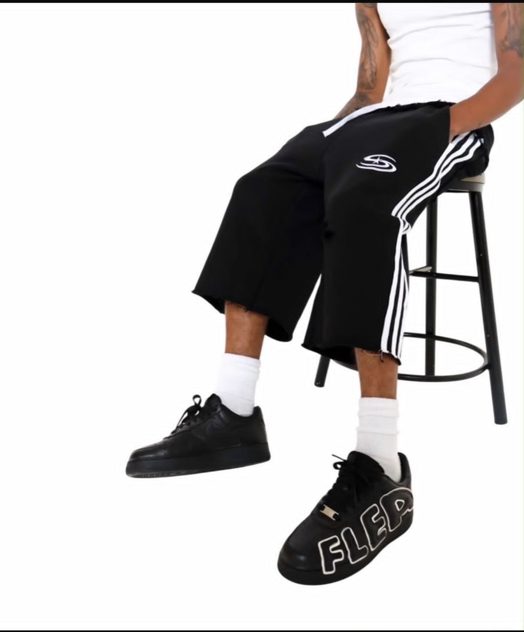 Model wearing black wide-leg cropped shorts with white side stripes and embroidered logo.